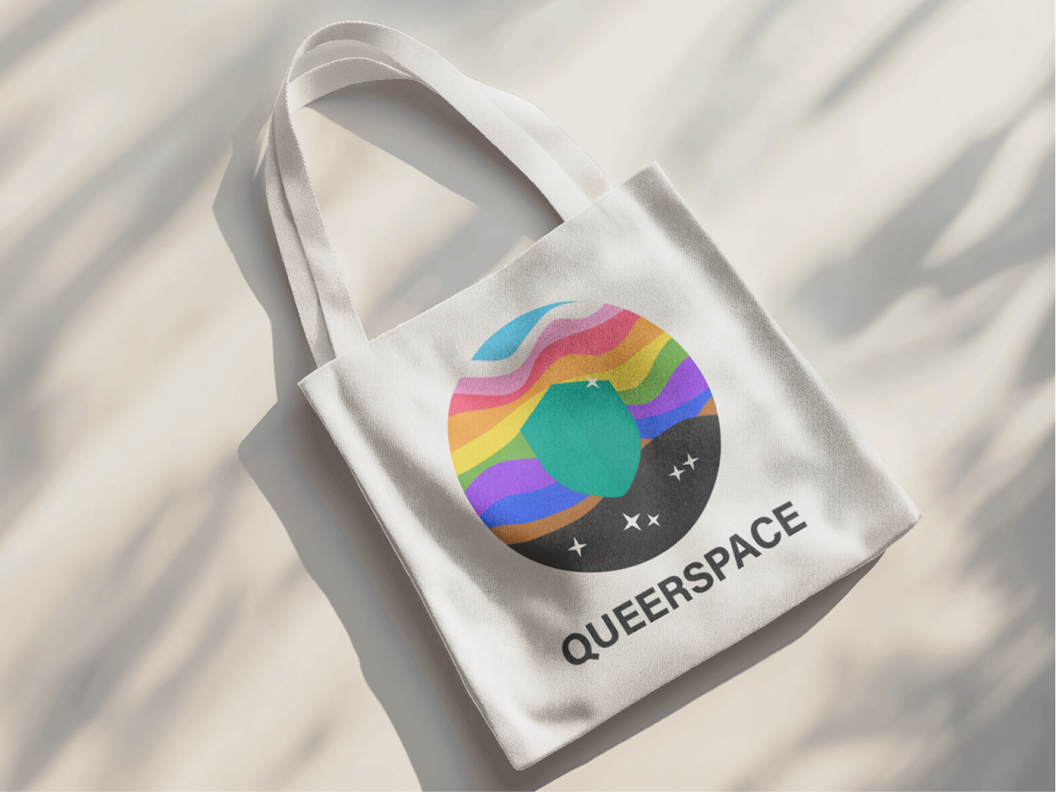 Natural cotton tote bag printed with the Queer Space rainbow shield identity